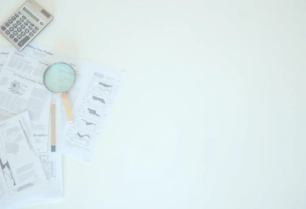 Documentos financeiros, calculadora e lupa em uma mesa, representando a regularização do MEI